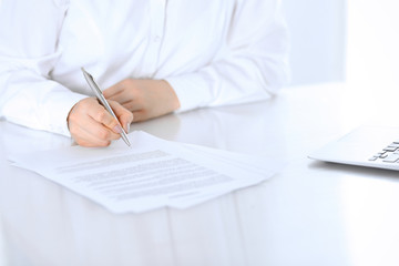 Fototapeta premium Close-up of female hands with pen over document, business concept. Lawyer or business woman at work in office