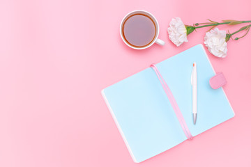 workspace desk styled design office supplies, hot tea and white flower on pink pastel background minimal style