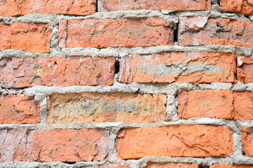 The destroyed wall of red brick with the remains of concrete solution close up. Texture rough, background