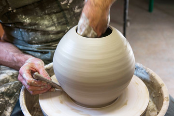      Artist potter in the workshop creating a ceramic vase. Hands closeup. Twisted potter's wheel. Small artistic craftsmen business concept. 