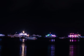 Fototapeta premium Beautiful night sky with skyscrapers in Jomtien beach Pattaya, Thailand, Crowd of people are relax on the beach in the night, Tourist are walking on the beach with cool wind air from sea