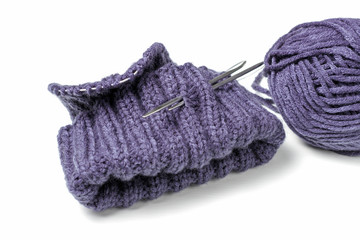 Knitted hat, knitting needles and skein on a white background