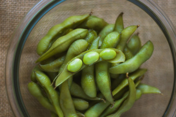 close up portrait of Japanese food edamame nibbles, boiled green soybeans 