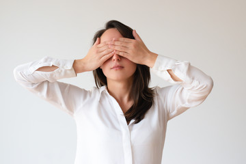 Serious serene young woman covering eyes with hands. Birthday girl ready for surprise. Surprise concept