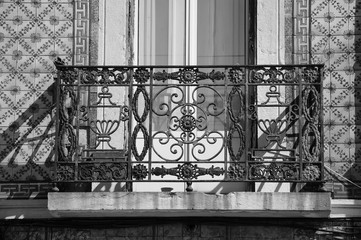 Rusty forging balcony and ceramic tiles (azulejos) wall. Architectural detail of typical old building in the centre of Lisbon (Portugal). Black and white photo..