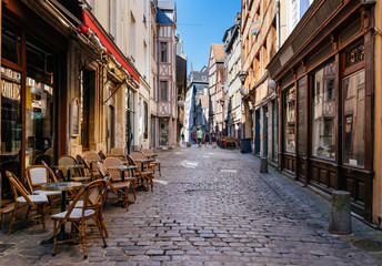 Fototapeta na wymiar Cozy street with timber framing houses and tables of restaurant in Rouen, Normandy, France