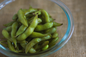 close up portrait of Japanese food edamame nibbles, boiled green soybeans 