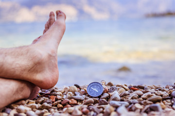 Compass and mans feet on beach, enjoy and text space
