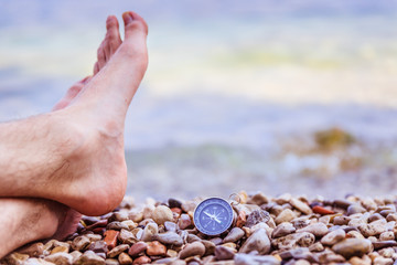 Compass and mans feet on beach, enjoy and text space