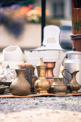 Antique teapots, creamer and other utensils at a flea market. Old metal tableware at a garage sale.