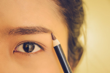 Naklejka premium Beauty face of Asian woman by applying eyebrow pencil and smooth skin by cosmetics.