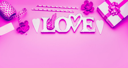 Naklejka premium Word Love with gift box, hearts and decorations on neon color background with greeting card and copy space, top view, Flat lay. Valentines day greeting and shopping sale, abstract love symbol template