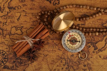 Vintage compass and cinnamon spices on a old world map - trade and explorer concept
