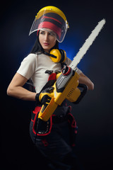 Obraz na płótnie Canvas brunette girl in special clothes and a worker in a helmet posing on a black background with a working tool