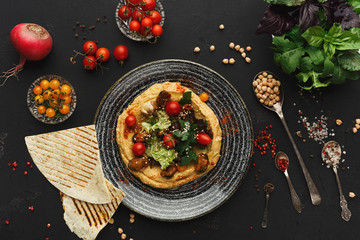 Hummus with vegetables and seafood on black background