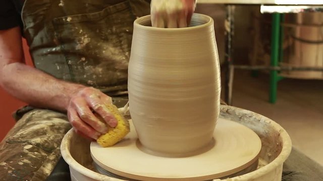 Artist potter in the workshop creating a ceramic vase. Hands detail closeup. Twisted potter's wheel. Small artistic craftsmen business concept. 