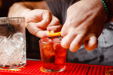 Barman is decorating a Negroni orange cocktail