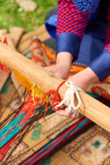 Weaving of handmade carpets closeup. Women's hands behind a loom.