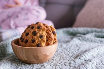 Home baking and baby. The little girl eats cookies on the couch. Photo vintage with natural light. Free space for text.