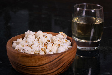 Salt popcorn and whiskey glass on the marble table, selective focus