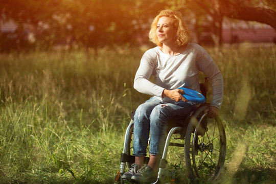 Woman in wheelchair throws frisbee