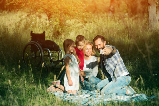 Happy Family Taking Selfie On The Picnic In Park. Paraplegic