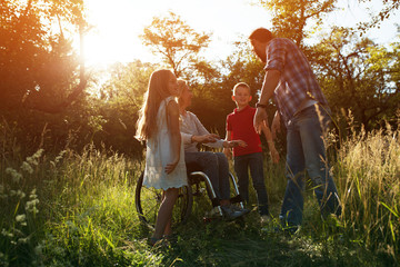 Woman in an armchair has fun with her husband and two children in park
