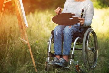 Woman in wheelchair drawing on easel outside