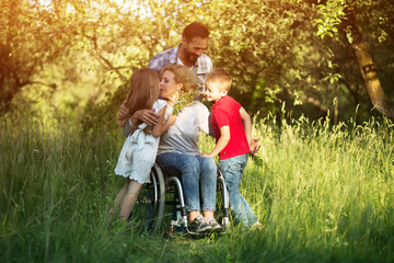 Woman in wheelchair kisses her son among family members