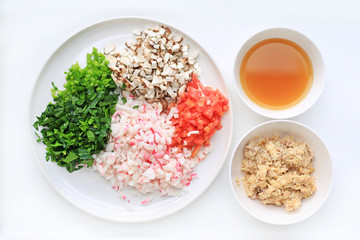 Chopped vegetables with soup and mash fish on white plate against white background.