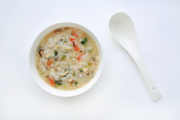 Porridge for baby food in white ceramic bowl and spoon on white background.