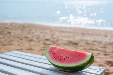 Watermelon on a background of a sandy beach and the sea.