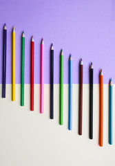 Colour pencils lying on pastel purple and beige background. Back to school concept. Colorful art studying and painting process. Drawing with pencils. Copy space place for postcard wish.