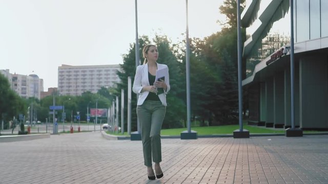 Business woman in heels walks down the street, stumbles, drops documents, and puts them in order. Fail. Slow motion