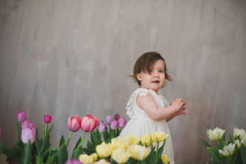 Obraz na płótnie Canvas Beautiful smiling baby girl among the tulips.