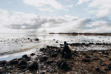 Anonymous tourist with cup of coffee against lake in Iceland