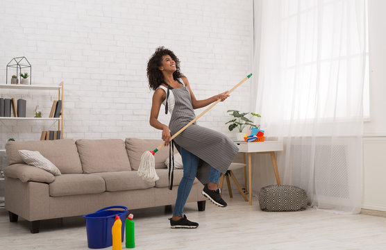 Black woman playing air guitar with mop