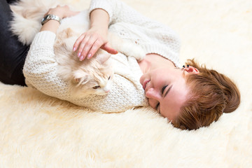 Young woman is playing with her cat