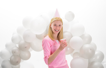 Obraz na płótnie Canvas Beautiful girl in birthday hat with balloons. Happy woman in party cap with white air balloons and cup of fruit juice. Joyful model having fun. Christmas, New Year, birthday party celebration.Emotions