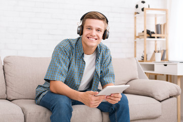 Happy teen guy watching videos on digital tablet
