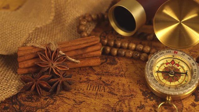Vintage compass with spyglass telescope and cinnamon spices on an old world map - trade and explorer concept