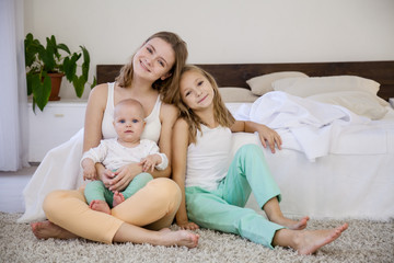 three girls sisters in the morning in the bedroom on the bed play