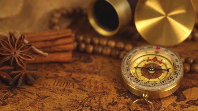 Vintage compass with spyglass telescope and cinnamon spices on an old world map - trade and explorer concept