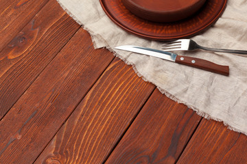 Empty plate and towel over wooden table background.