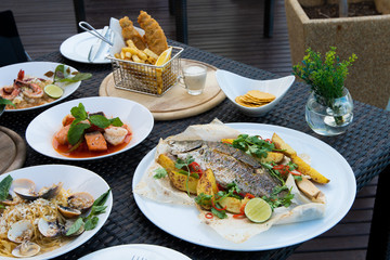 Many Food plate of Baked Scallop Mussel, Spaghetti Crap meat, Seabass fish with potato, Fried Chicken Fish Salad, Shrimp with cut salmon fried, arrange on table top view set up for photo shoot