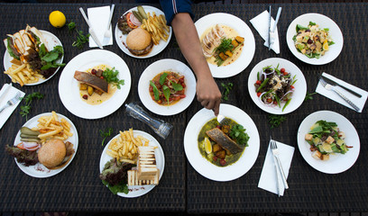 Mix Various Seafood, Spaghetti, club sandwich, burger, salad, hot spicy Foods on table over tropical ocean atmosphere, Top view camera dinner lunch together with friends family