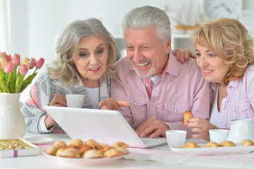 Happy senior people with laptop drinking tea