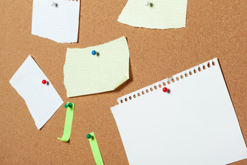 colorful sticky notes with pushpins and blank space,  on cork background