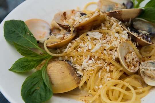 Spaghetti Crap meat with Baked Scallop Mussel on white plate, Fusion food stylish arrange on glass table along ocean mangrove tree Island, empty copy space for text logo