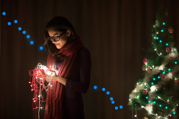 Young woman holding fairy lights of Christmas celebrations	